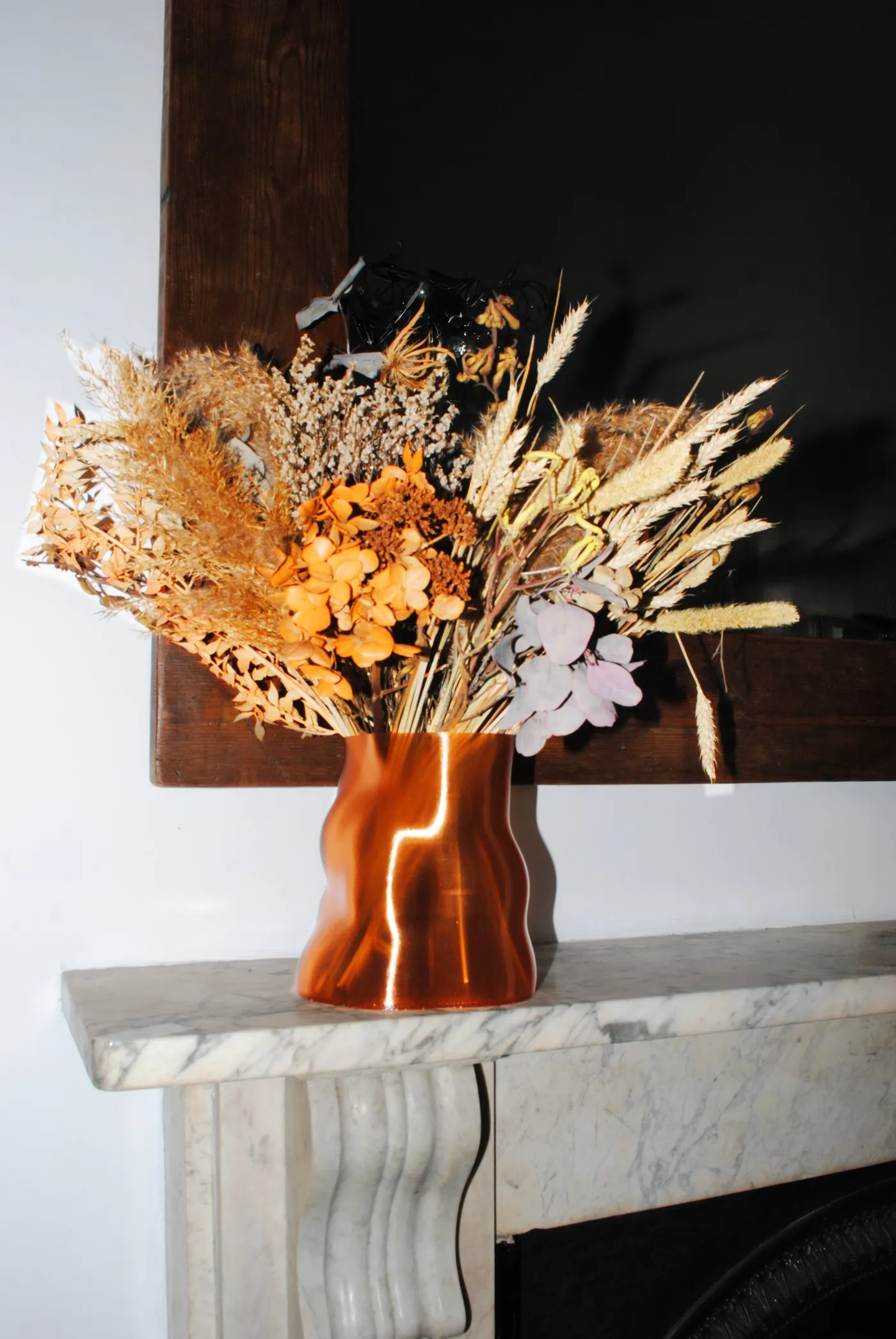 Peski vase in Copper Orange with dried flowers on a marble mantelpiece