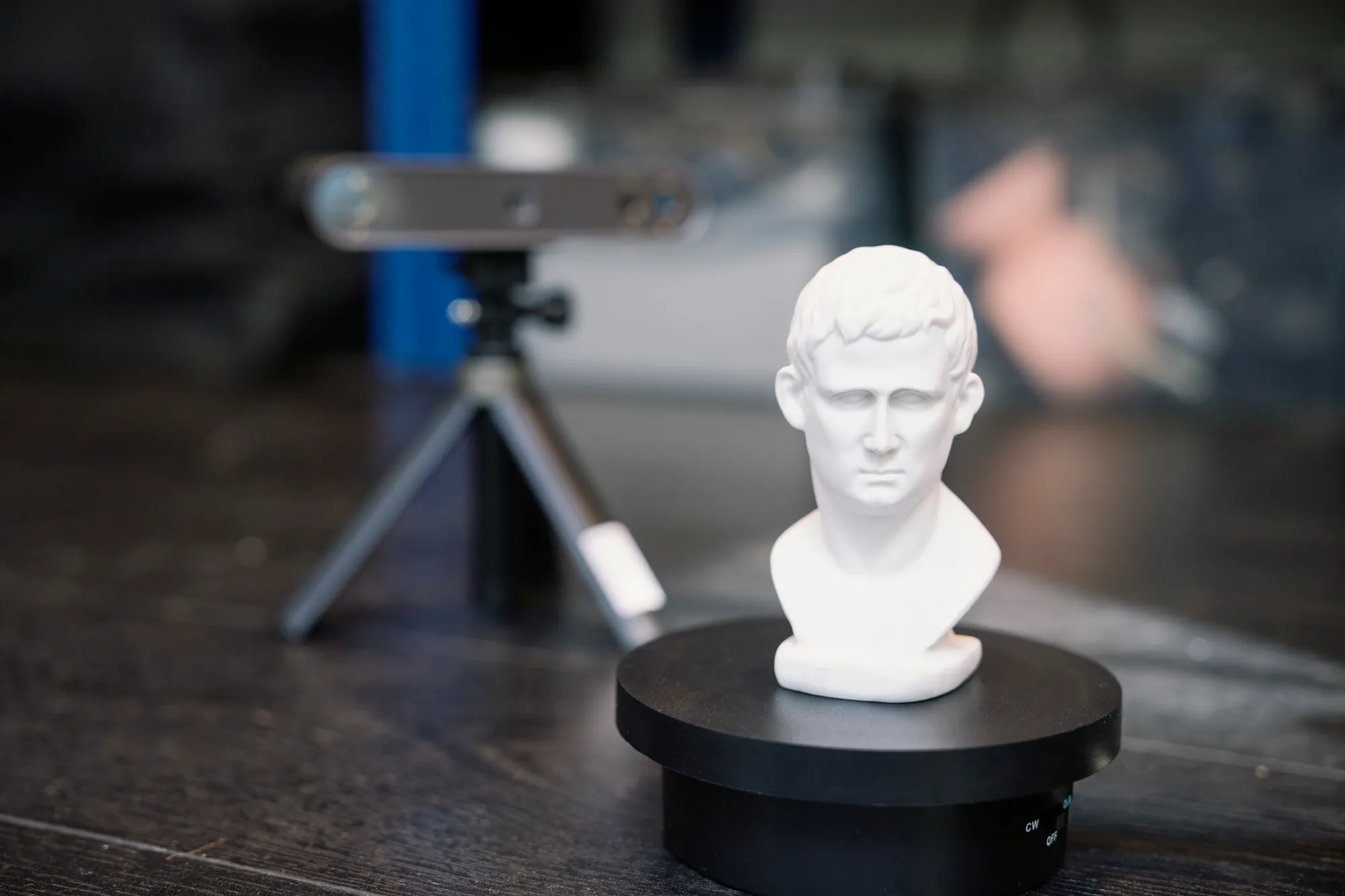 A 3D scanner on a tripod capturing a plaster bust on a turntable in the Spike TM studio
